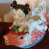 Pair of Asian Baby Laying on top of a Koi Fish Figurines
